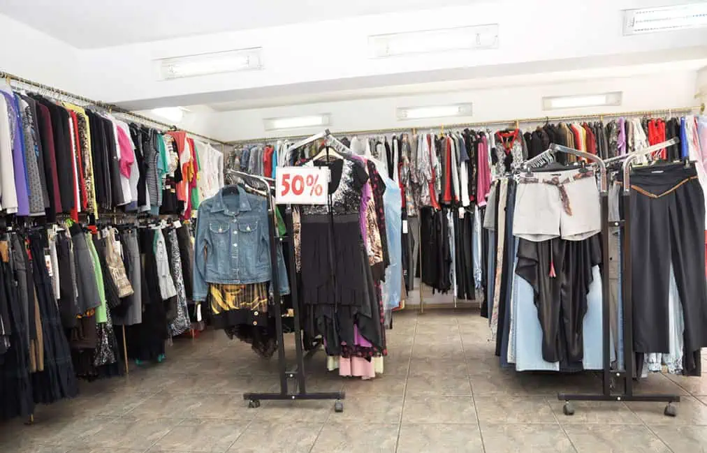 Interior of a clothing store with racks of various style garments and a "50% off" sign displayed prominently.
